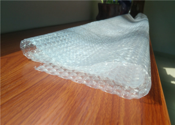 A long folded sheet of bubble wrap on wooden table.