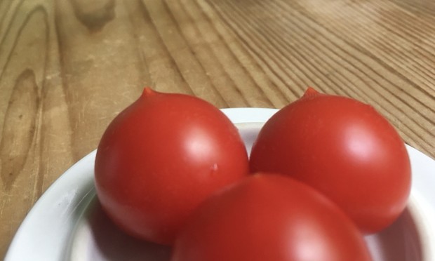 Auf dem Tisch ein Keramikschälchen, darin drei kleine Tomaten - knallrot und mit neckischem Zipfel.