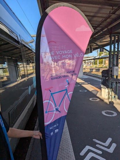 Fähnchen auf dem Bahnsteig mit Hinweis auf Platz für Fahrräder im Zug vor der entsprechenden Zugtür