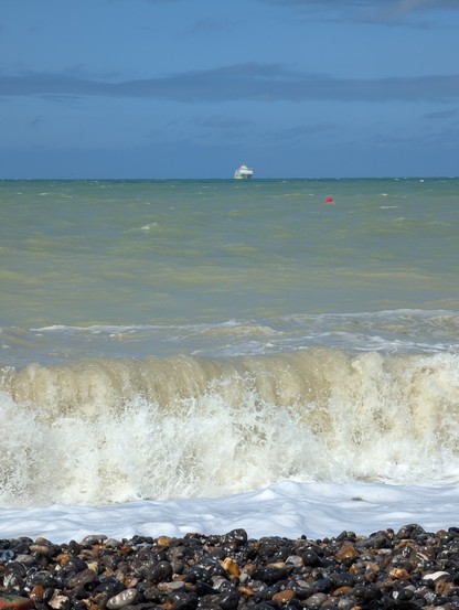 Steinstrand, hohe Wellen, eine Fähre