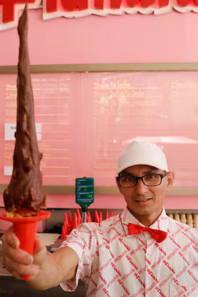 An ice-cream salesman handing a 60cm ice-cream cone over the counter.