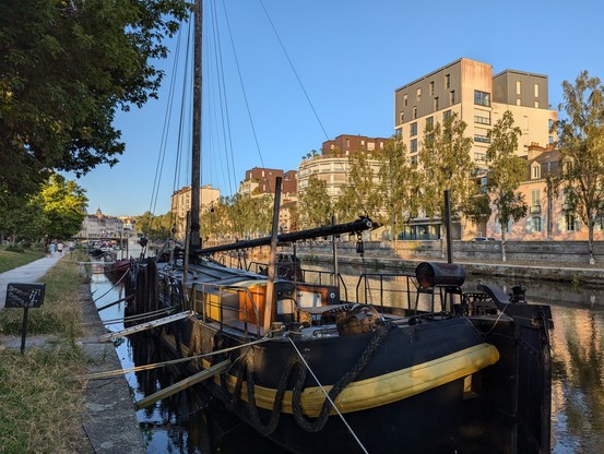 Eine Peniche liegt vertäut am Ufer eines Kanals in der Stadt