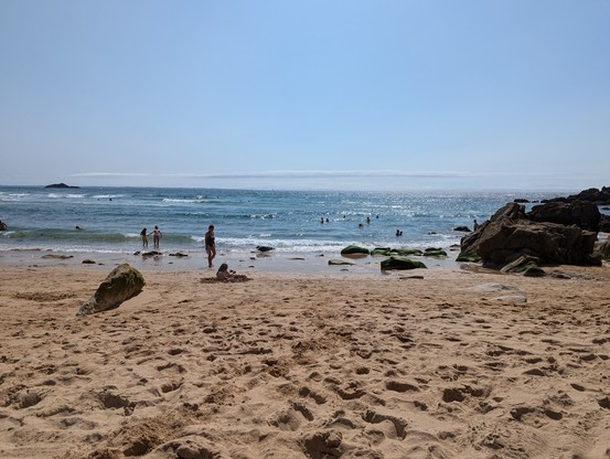 Blick über einen Sandstrand aufs Meer bei Sonnenschein und blauem Himmel