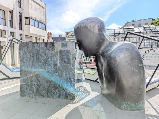 Eine Skulptur mit einem Kof und einen großen Steinblock